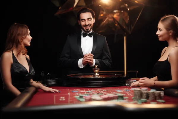 A professional dealer in a tuxedo greeting players at the roulette table, symbolizing the authentic live casino feel at BDOK.